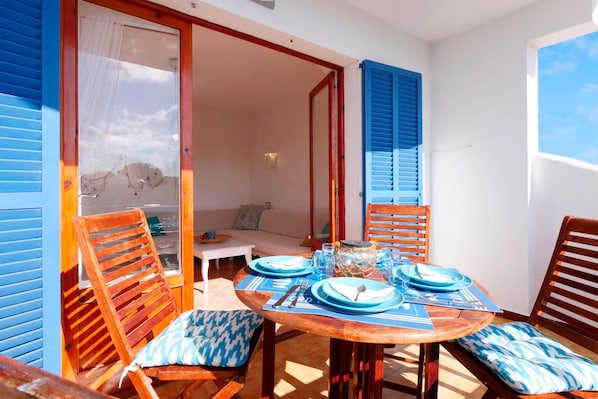 Un coin repas avec une table ronde en bois, dressée pour quatre personnes, recouverte d’une nappe bleue, et agrémentée de chaises assorties.