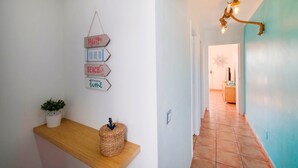 Ein Flur mit einem Holzregal, einem an der Wand befestigten Schild mit motivierenden Sprüchen und einer Pendelleuchte.
