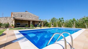 Una piscina con una casa de piedra al fondo.