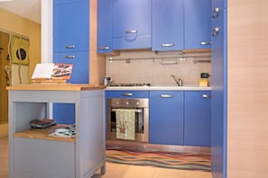 Uma cozinha moderna com armários azuis, um forno de aço inoxidável e um tapete colorido.