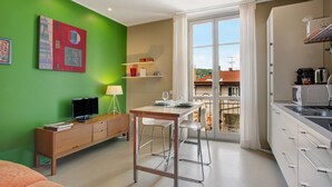 A modern room with a dining area, kitchenette, and a large window with a view. - Delightful Holiday Apartment Steps from the Port with Mountain Views (como)