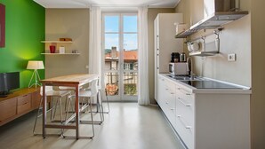A modern kitchen with a dining area, a balcony with a view, and a green accent wall. - Delightful Holiday Apartment Steps from the Port with Mountain Views (como)