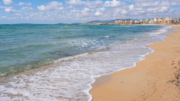 A beach with clear waters, a sandy shore, and a distant cityscape. - Holiday Home "Ana House" with Sea View, Wi-Fi & Terrace (CAN PASTILLA)