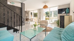 Un salon moderne avec un escalier, une table basse en verre, un canapé et un téléviseur.