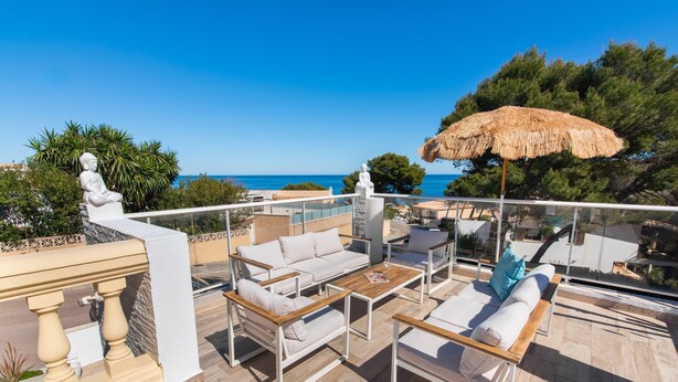 Une terrasse sur le toit, aménagée avec du mobilier d’extérieur, une statue et offrant une vue sur la mer.
