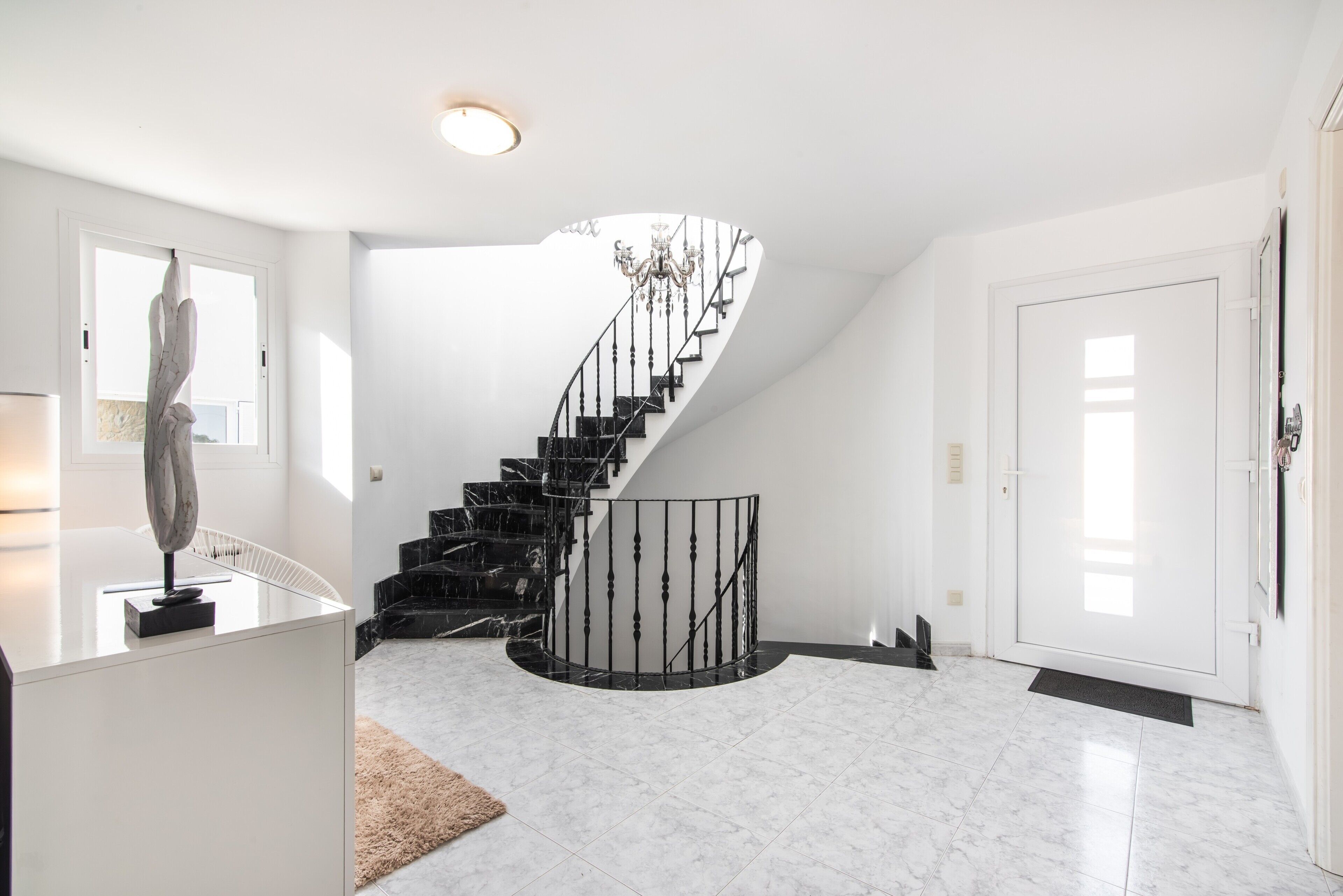 Un intérieur moderne avec un escalier à volutes, un lustre et un design minimaliste.