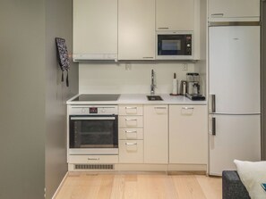 A compact kitchen with a built-in oven, microwave, and a refrigerator.
