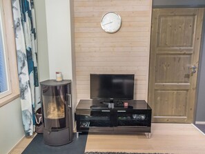 A living room with a flat-screen TV, a small table with a candle, and a wooden door. - Levin stara c11 by Interhome (Kittilä)