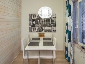 A dining area with a white table and chairs, a decorative wall piece above, and a window with curtains. - Levin stara c11 by Interhome (Kittilä)