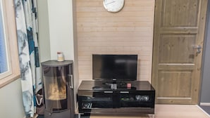 A living room with a wooden panel wall, a clock, a television, a fireplace, and a door.