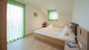A bedroom with a bed, a desk, a chair, and a window with curtains.