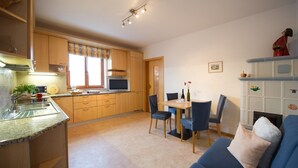 A compact kitchen with a dining area, a sofa, and a fireplace.
