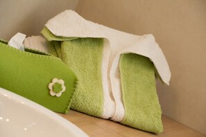 Une salle de bain avec une serviette verte et une serviette blanche posées sur une surface en bois.