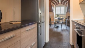 Eine moderne Küche mit Holzschränken, einer schwarzen Arbeitsplatte und Blick in einen Essbereich mit Tisch und Stühlen.