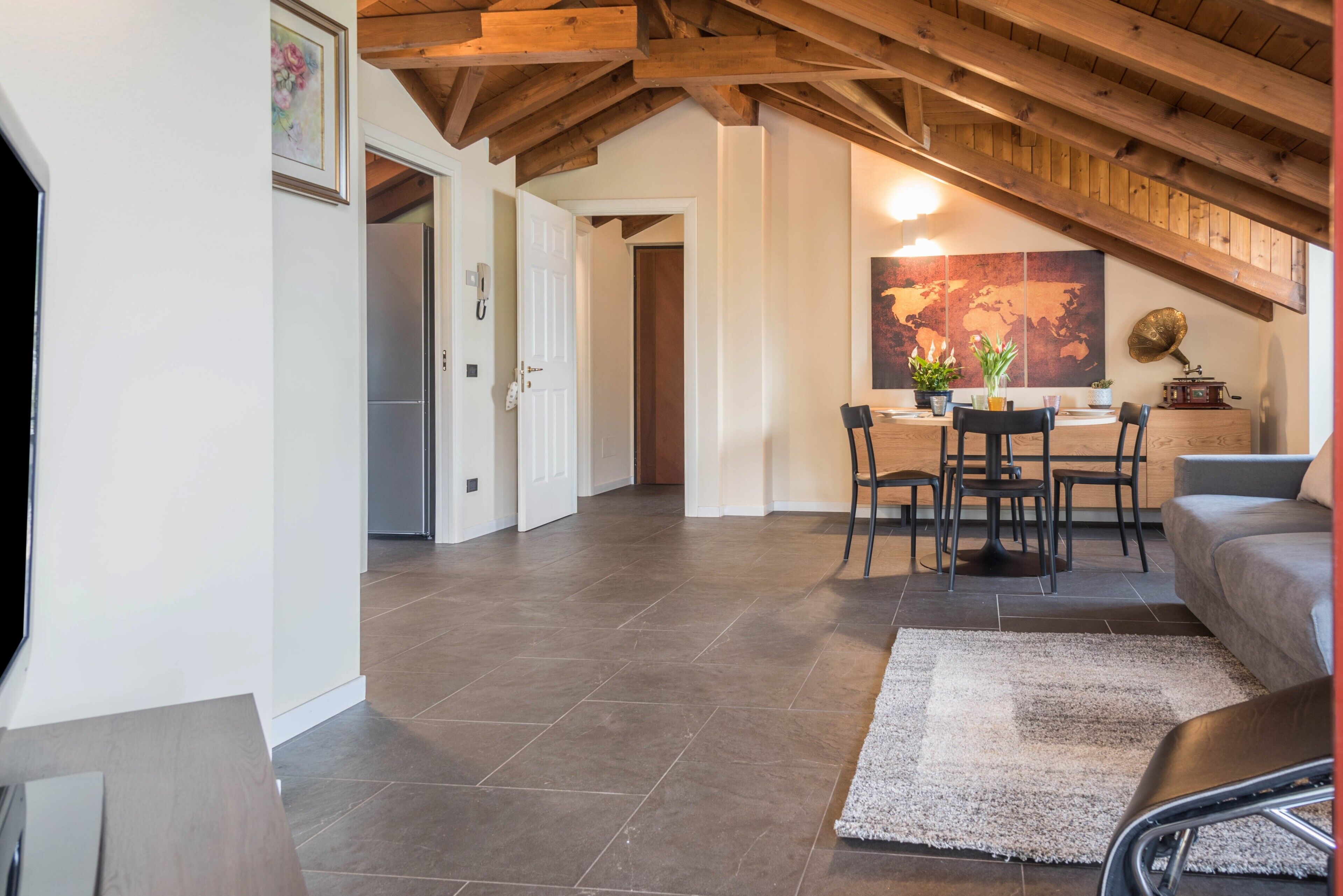 A spacious room with a high ceiling, a dining area with chairs and a table, and a sofa.