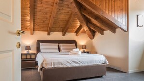 Ein Schlafzimmer mit einem großen Bett, Holzbalken an der Decke und einem Nachttisch mit Lampe.