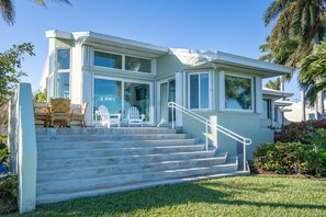 A modern two-story house with a large front porch, a staircase leading to the entrance, and a well-maintained lawn.