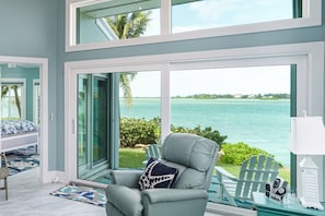 A room with a large sliding glass door leading to a view of the ocean.
