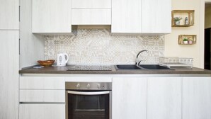 A modern kitchen with white cabinetry, a patterned backsplash, a built-in oven, and a sink with a faucet. - Silvia Loft on Hill between Green & White Coast (Portoferraio)