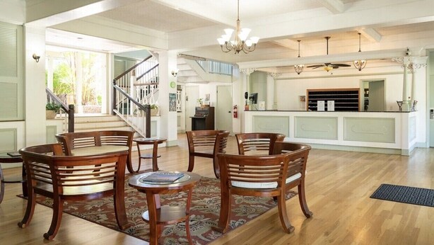A spacious living area with a wooden dining set, a chandelier, and a view of the kitchen.