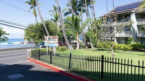 A beachfront hotel with a signboard, palm trees, and a view of the ocean.