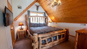 A rustic bedroom with a wooden bed frame, a mounted deer head, and a ceiling fan. - Ridgetop Lakeview - Bedroom Cabin on Lake Nantahala w/ Private Deck (Topton)