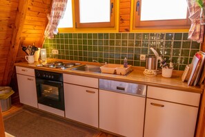 Une cuisine avec des meubles de rangement en bois, un lave-vaisselle, une cuisinière et une fenêtre avec des rideaux.