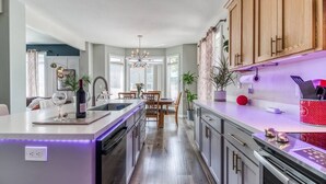Una cocina moderna con una isla central, armarios de madera y un comedor con mesa y sillas.