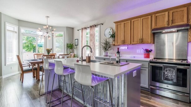 Una cocina moderna con una isla central, armarios de madera y electrodomésticos de acero inoxidable.