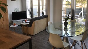 Een moderne woonkamer met een bank, televisie en een glazen eettafel met stoelen.