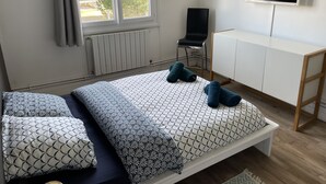 Een slaapkamer met een bed, een televisie, een stoel en een kast.