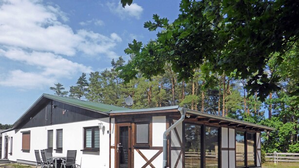 A modern building with a covered patio, large windows, and a satellite dish. - Ferienwohnung 1 - Ferienhaus am Waldessaum (Fuhlendorf)