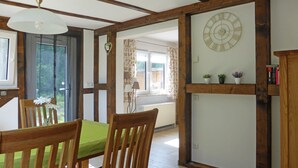 A dining area with wooden furniture, a green tablecloth, and a clock on the wall. - Ferienwohnung 1 - Ferienhaus am Waldessaum (Fuhlendorf)