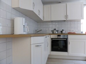 A modern kitchen with white cabinets, a built-in oven, and a coffee maker on the countertop.