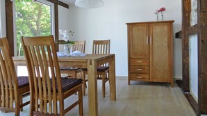 Un comedor con muebles de madera, una mesa, sillas, un armario y una lámpara colgante.