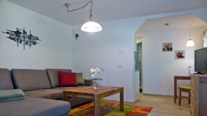 Una sala de estar con un sofá, una mesa de centro, un televisor y una alfombra colorida.