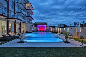A swimming pool with a water feature and a building with balconies.