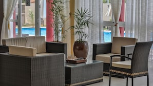 A seating area with wicker furniture, a chessboard, and a large vase. - Menabe'l (Antsirabe)