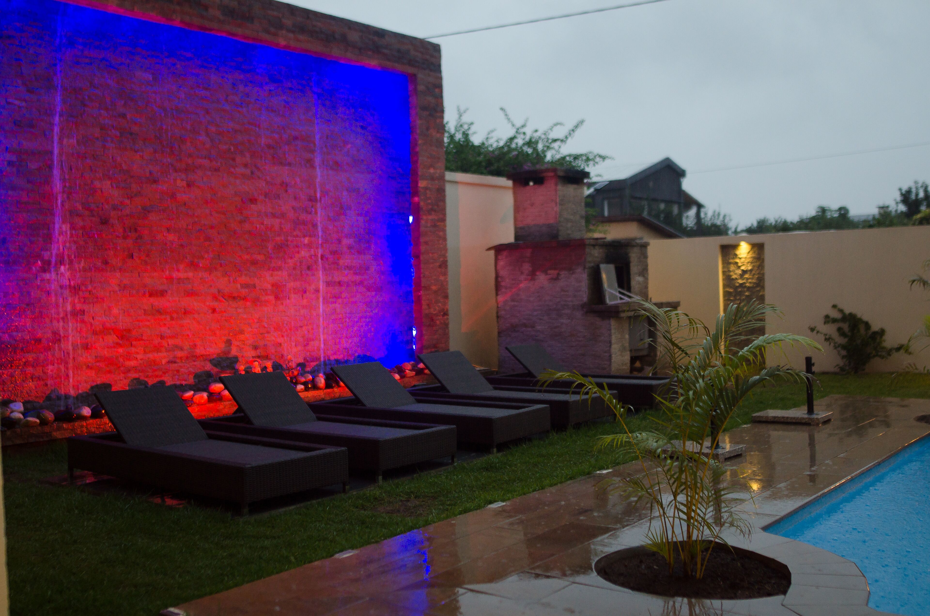 Zona junto a la piscina con sillas de descanso y una fuente.