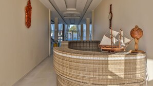 A hallway with a woven bench, a ship model, and a wooden sculpture. - Menabe'l (Antsirabe)