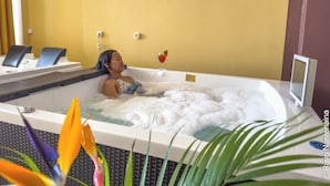 A woman relaxing in a hot tub with a drink and a tablet. - Menabe'l (Antsirabe)