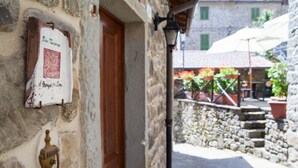A stone building with a wooden door and a wall-mounted sign. - Borgo dei Corsi - RIBUSTINO 2 Apartment (Raggiolo)