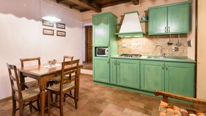 A kitchen with green cabinets, a wooden dining table, and chairs. - Borgo dei Corsi - RIBUSTINO 2 Apartment (Raggiolo)