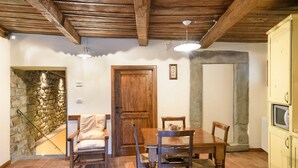 Un comedor con una mesa y sillas de madera, una pared de piedra y una puerta de madera.