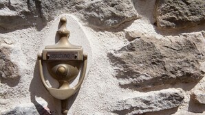 Un hidrante de bronce con la etiqueta "RIBUSTINO" sujeto a una pared de piedra.