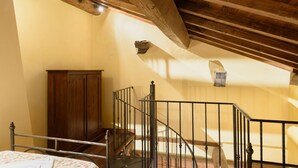 Quarto com teto de madeira, cama, guarda-roupa e escada.