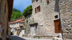 A narrow stone street with traditional buildings, a bench, and a wooden door.