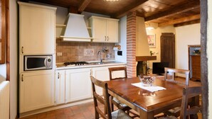 Une cuisine avec des meubles blancs, un four à micro-ondes, une cuisinière et une table à manger avec des chaises.