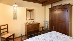 Une chambre à coucher avec un lit en bois, une commode, une chaise, un miroir et une armoire.