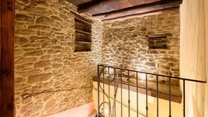 Une pièce aux murs de pierre, dotée d’un plafond en bois et d’une rambarde en métal.
